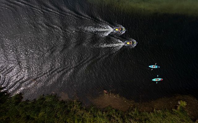 Aerial image of a pair of kayaks trailed by a pair of Jet Skis as they make their way north on the Torch River in northern Michigan