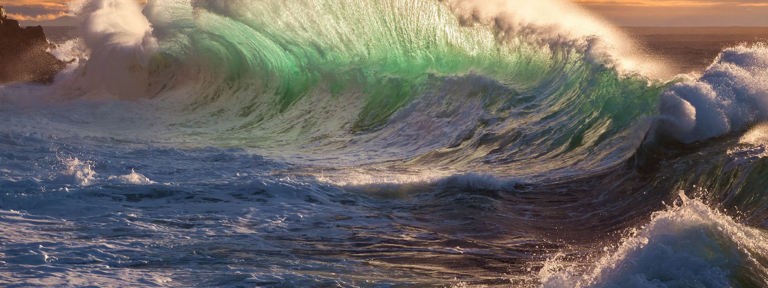 A massive wave breaks as the ocean swells towards the shore.