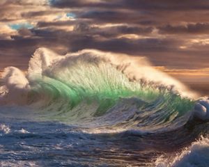 A massive wave breaks as the ocean swells towards the shore.