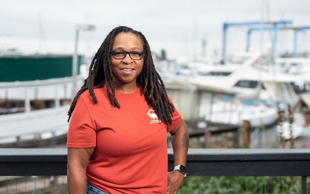 Candid portrait of Tia Clark standing at a dock with boats in the background.