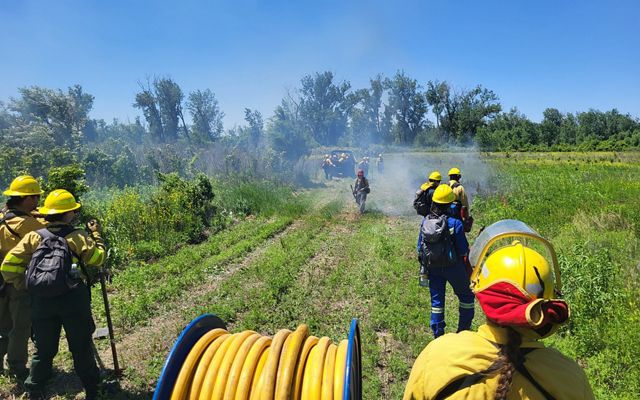 Women stand with fire tools while a UTV drives away.