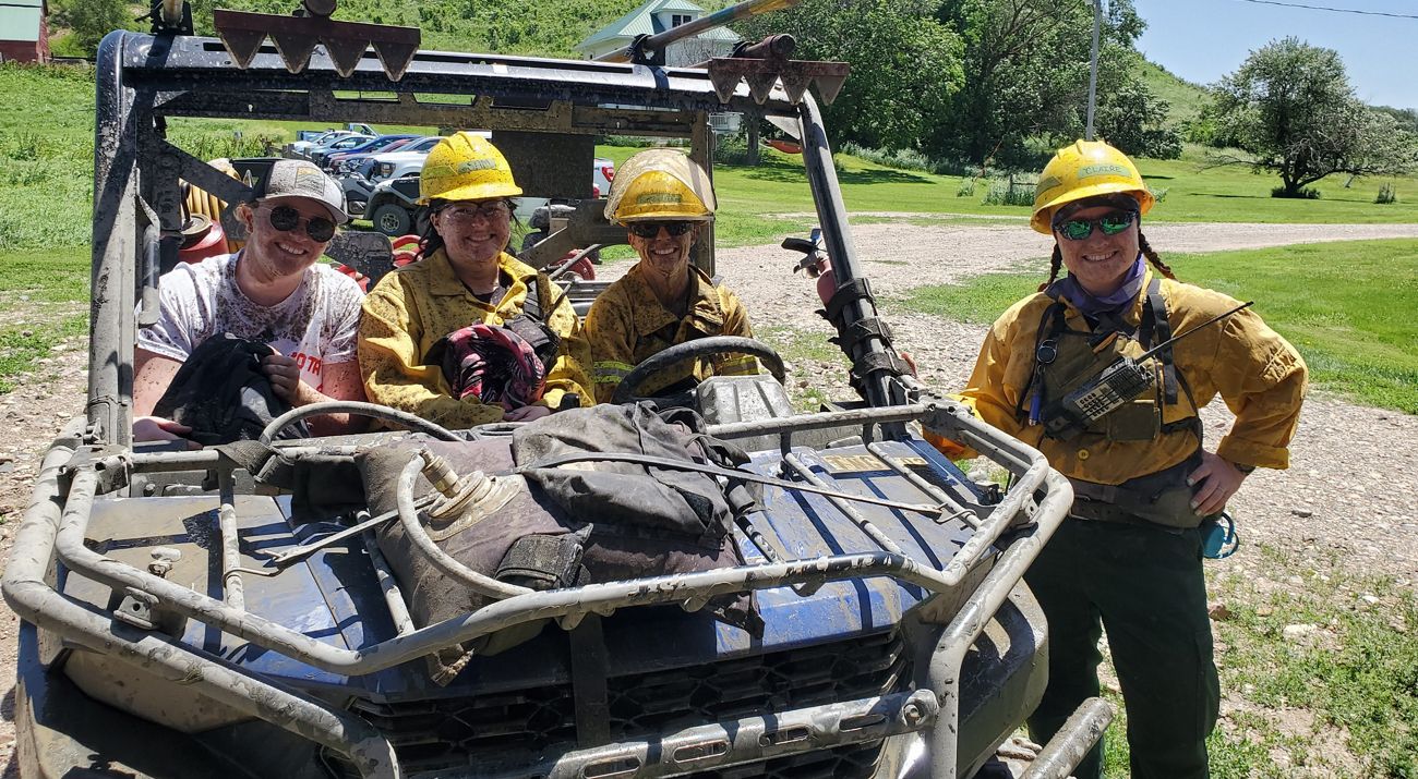 Women smile while sitting in a Utility terrain vehicle.