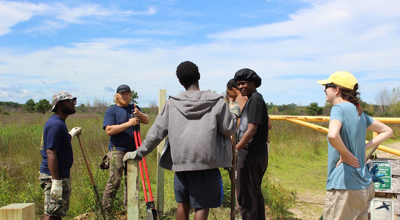 Volunteers from Tree Street Youth help spruce up signage at the Kennebunk Plains Preserve.