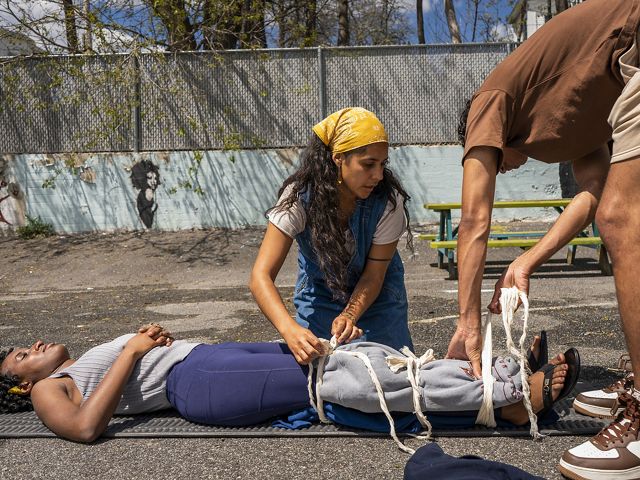 Two people practice splinting a third person's leg.