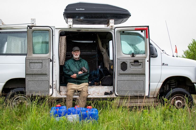 A man sits inside the open side doors of an Econoline van.