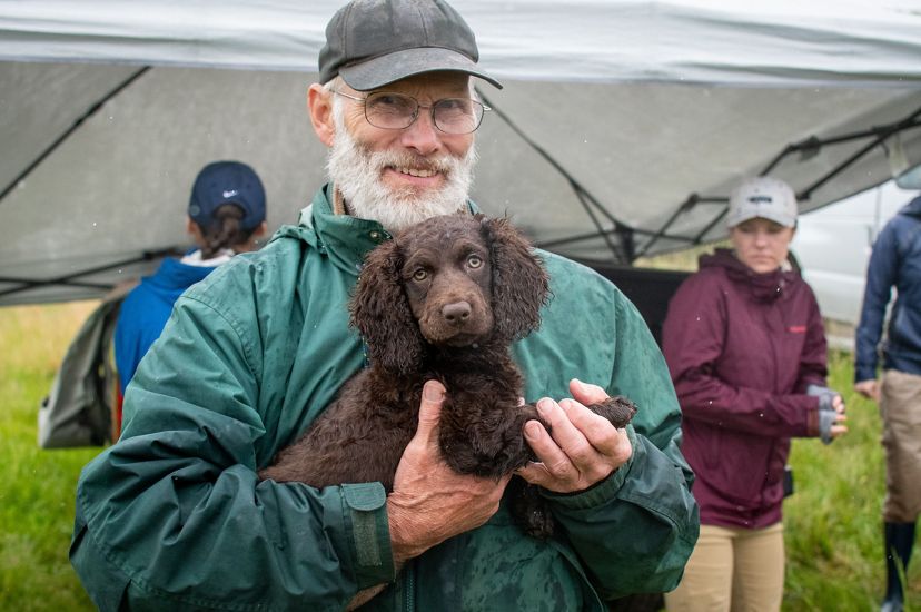 John Rucker holding a floofy brown puppy.