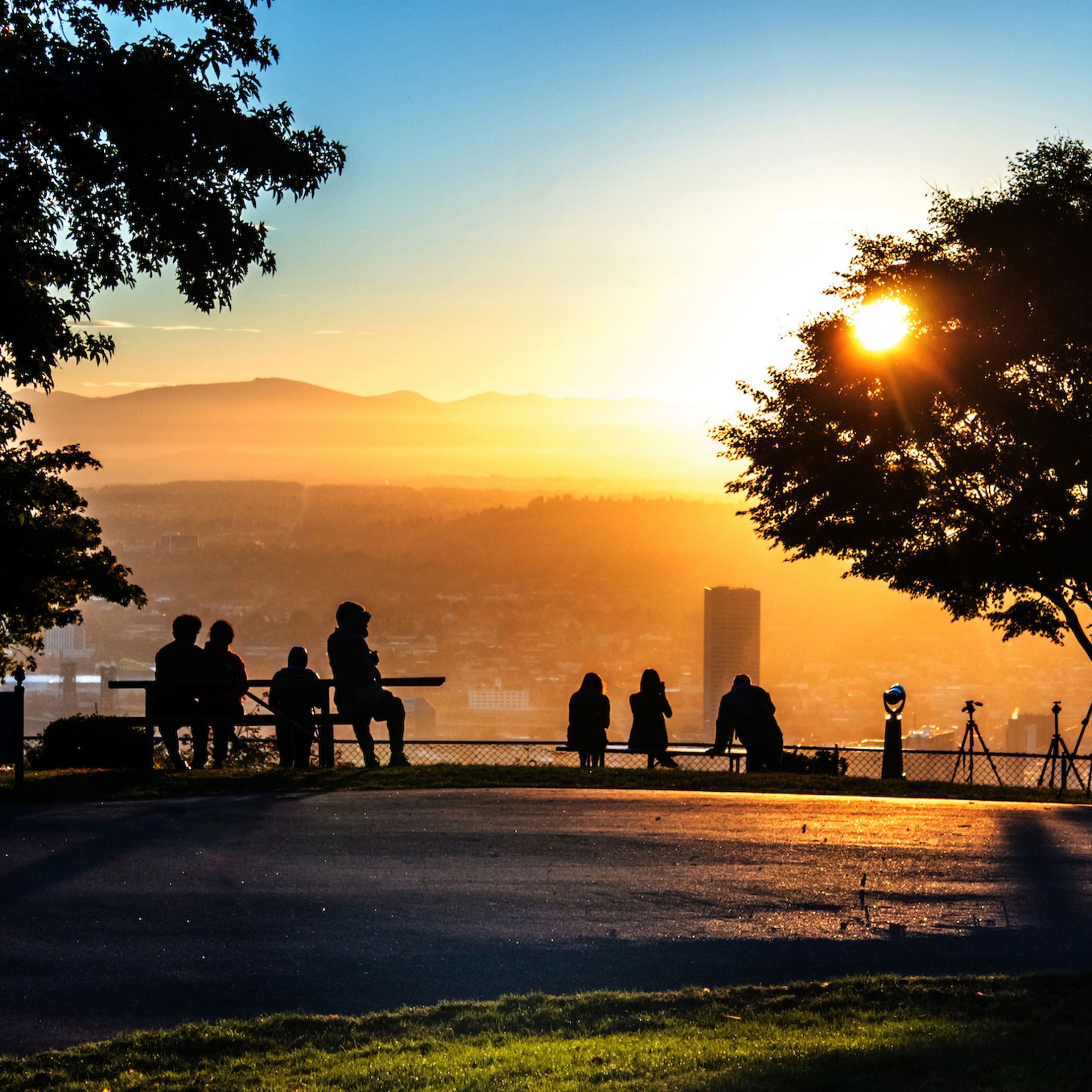 A group of people facing the sunset as they overlook the city of Portland. 