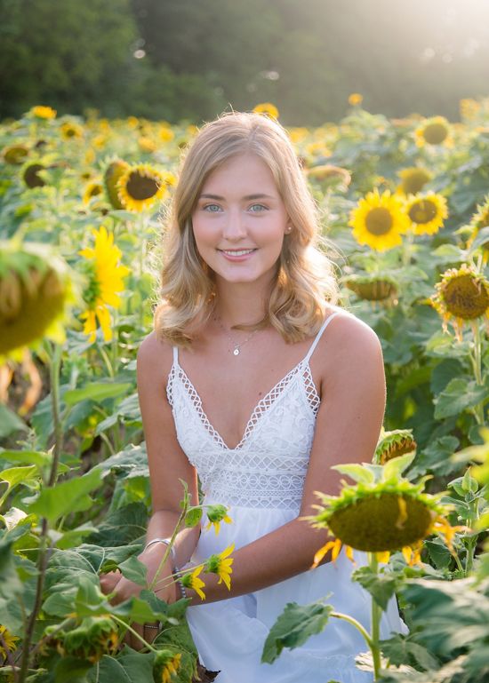 Candid headshot of Anna McCarter posing in a field of sunflowers.