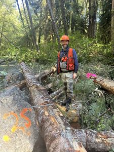 Kyle standing against logs