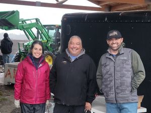 Three smiling people stand together.