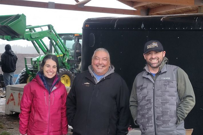 Three smiling people stand together.