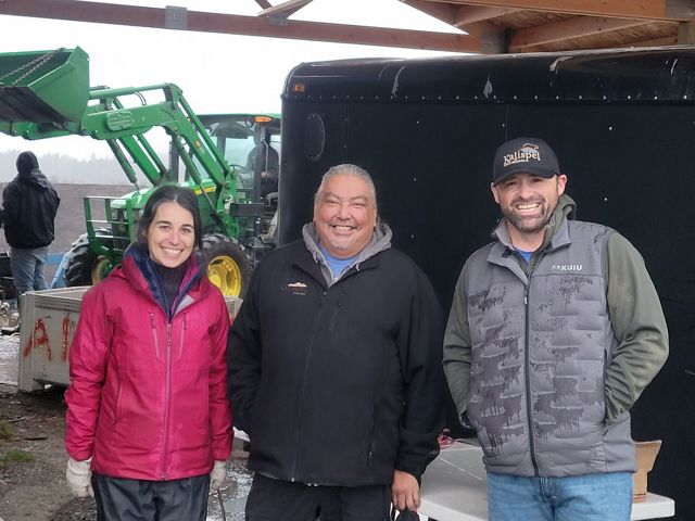 Three smiling people stand together.