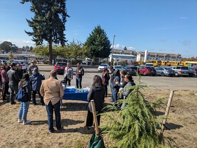 A group of people gather outside of a school and discuss urban trees.