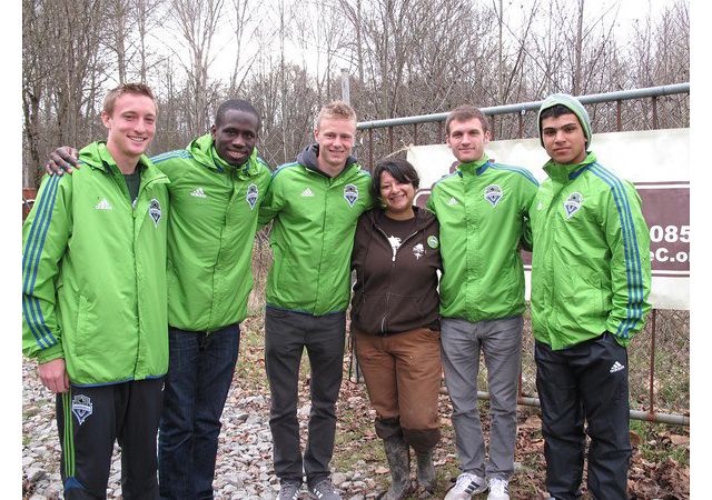 Six people, five in a bright green pullover, pose for a picture with Lylianna.