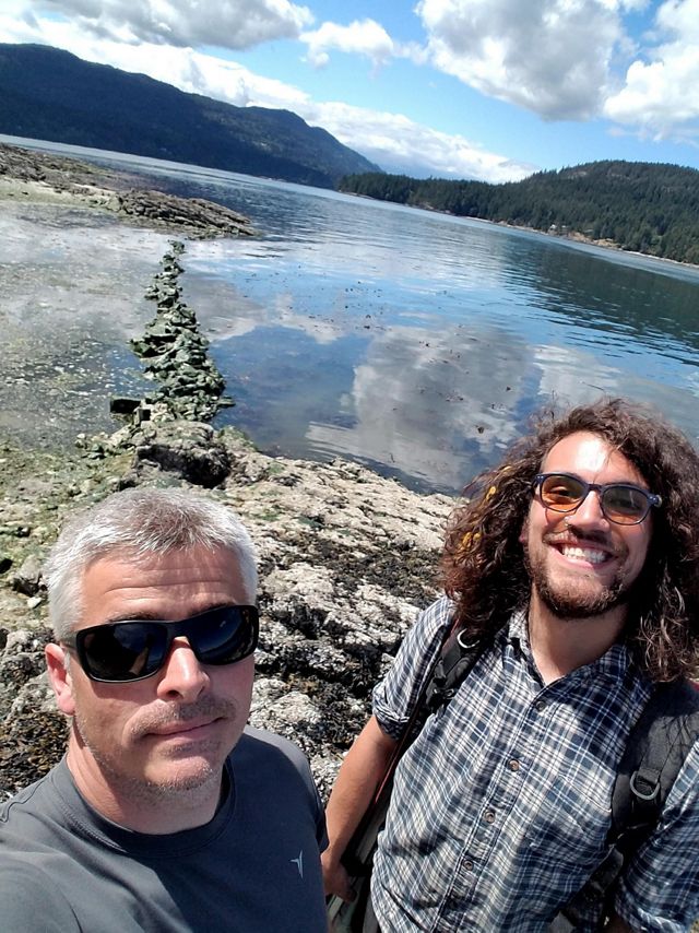 Marco Hatch and a student stand on the shore of a lake and pose for a selfie.