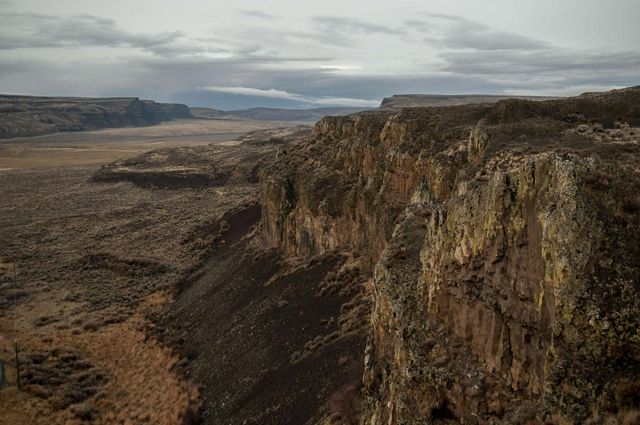 Landscape view looking across a red-brown gully running between tall cliffs.