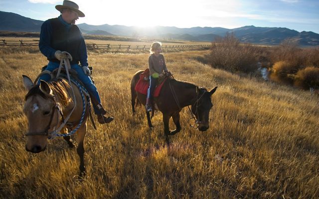 Two ranchers on horseback near sunset on an Idaho ranch.