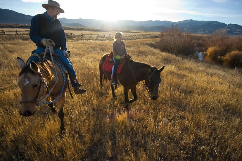 Two ranchers on horseback near sunset on an Idaho ranch.