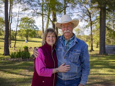 A man and a woman stand together in a field of green grass.