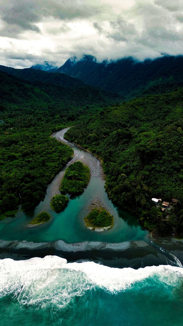 Turquoise waters meets a river with surrounding  mountains.