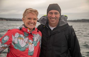Abbie Reynolds and Conrad Pilditch smile and pose together on a boat in the ocean.