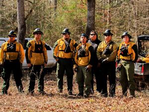 Seven members of the Alabama-Coushatta Tribe of Texas stand ready in their protective gear before a prescribed burn.