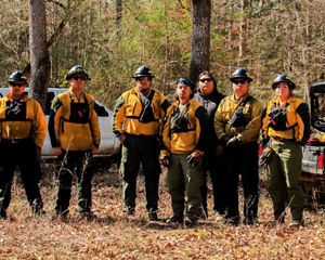 Seven members of the Alabama-Coushatta Tribe of Texas stand ready in their protective gear before a prescribed burn.