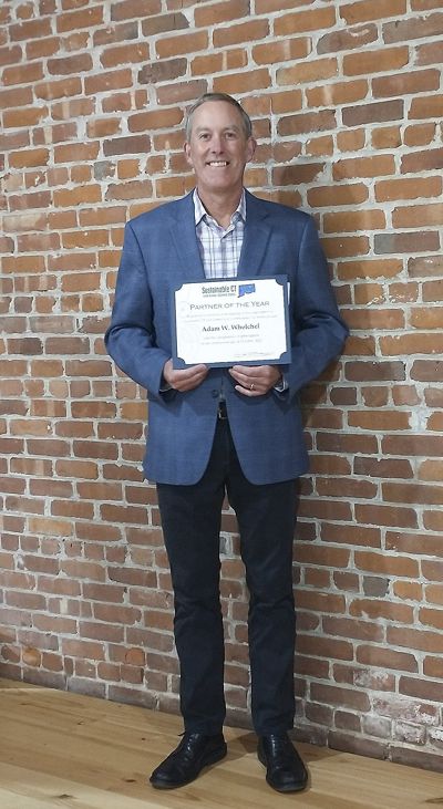 Photo of Adam Whelchel holding an award from Sustainable CT.