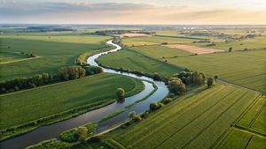 aerial image at sunset with farm fields and a river running through the landscape