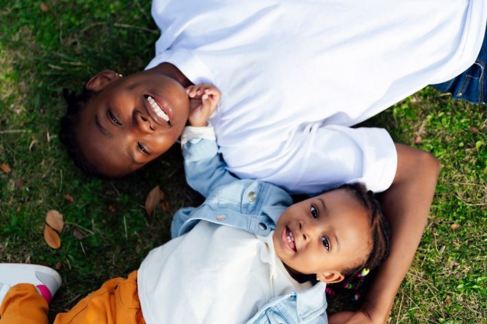 Two children lay in the grass laughing at the camera.