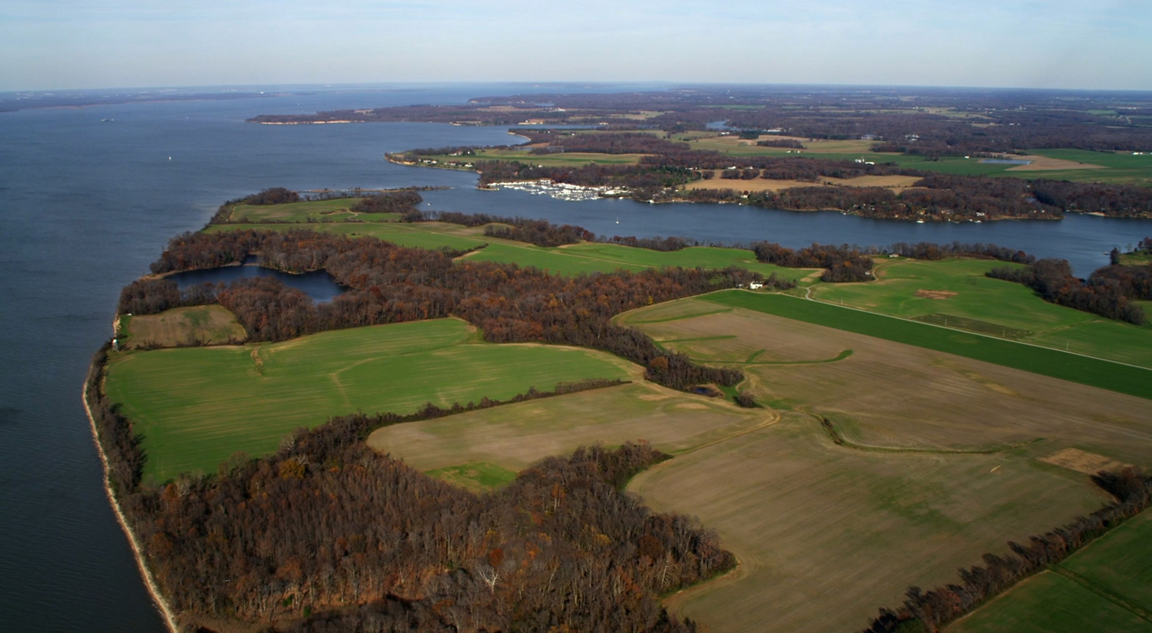 Aerial view of farmland on a wide finger of land extending into the Chesapeake Bay.