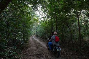Two people ride on a motorbike in the Noto Forest, in Lindi region of southern Tanzania, a miombo coastal forest protected by escapements. © Roshni Lodhia