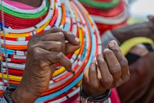 A close up of hands stringing together beads.