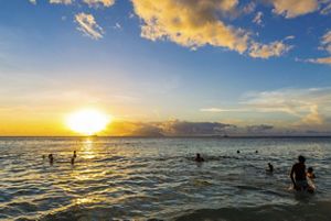Swimmers in the ocean at sunset.