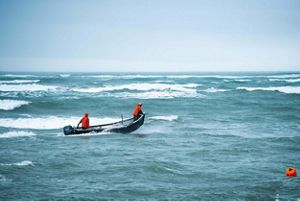 Two men wearing orange in a boat fishing for salmon.