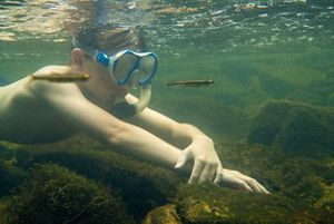 A boy swims underwater with a snorkle.