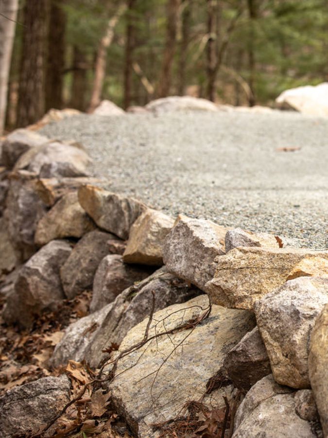 Closeup of rocks lining a gravel path in the woods.