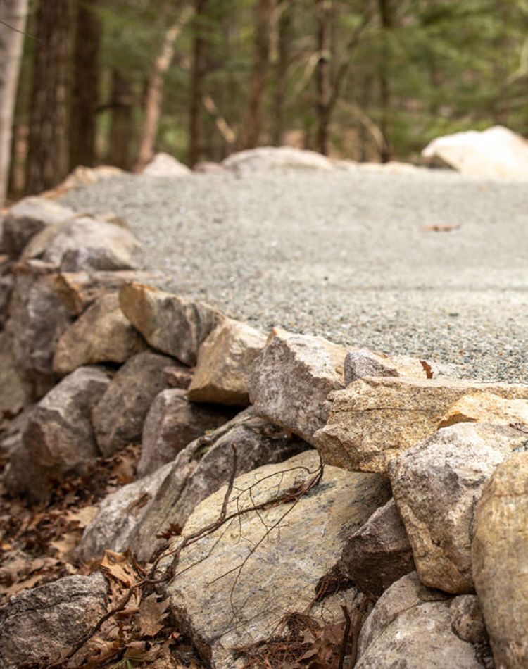 Closeup of rocks lining a gravel path in the woods.