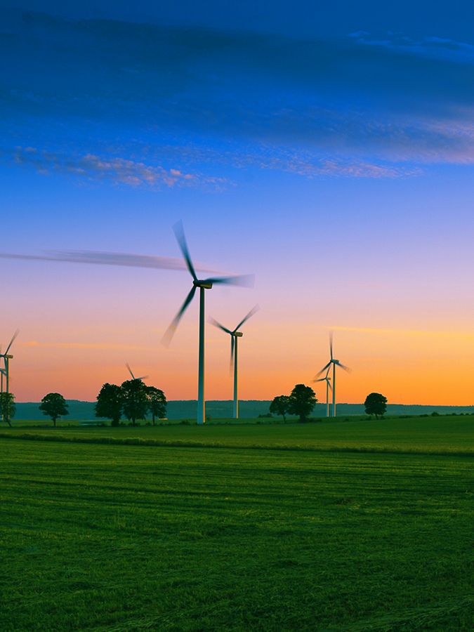 Wind turbines in farm field at dusk.