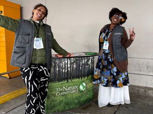 Two F2F canvassers hold up the peace sign while posing with a TNC banner. 