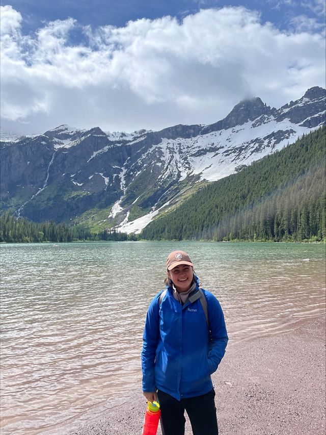 Amanda Cutler stands in front of a lake with snow- and pine-tree-covered mountains in the background.