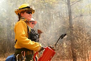 Andi Clinton holds a drip torch after igniting the margins of a burn unit during a controlled burn exercise at WTREX 2022.