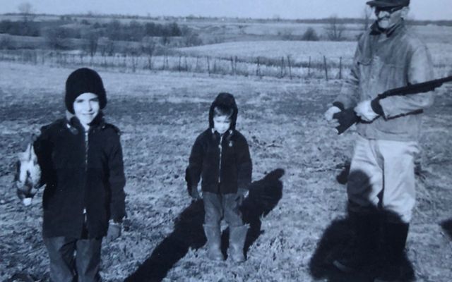 Old photo of two young boys and their grandfather on a farm. 