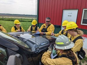 Interns circle around a truck for a briefing before a prescribed fire.