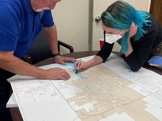 Two people work at a table over a map to determine locations for nature based solutions.