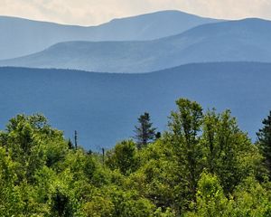 Rolling blue mountains in the background with bright green treetops in the foreground.