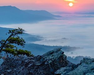 The sun rises over a foggy mountain valley.