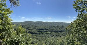 A blue sky and trees frames a mountain and surrounding valley.
