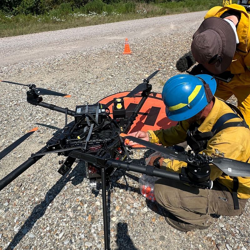 Two fire crew members working on a large drone.