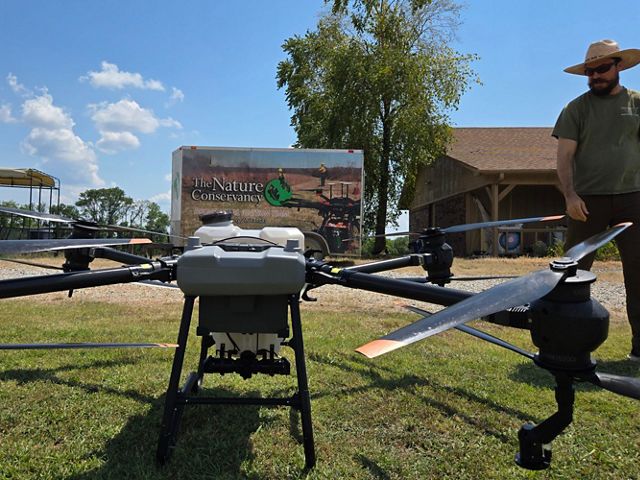 A large drone sits in a field in front of a trailer.